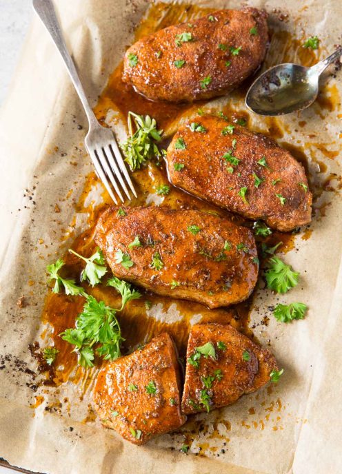 baked pork chops on baking sheet with parsley garnish